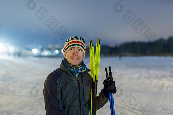 冬季森林中带着滑雪板微笑的男人的照片