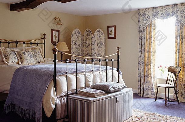 黄铜床下的条纹奥斯曼脚垫，浅蓝色的嵌入式乡村卧室，蓝色 白色的绒布折叠屏风和<strong>窗帘</strong>
