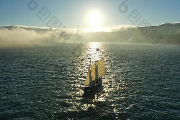 在旧金山湾日落时的纵帆船上有雾。