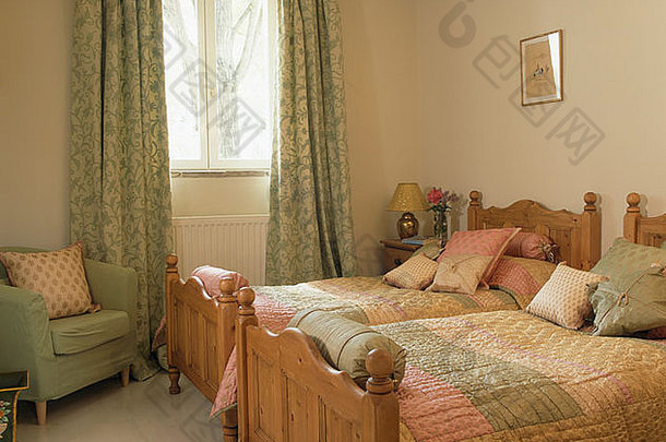 法国乡村卧室的双人木床上铺着拼花被子，有图案的绿色<strong>窗帘</strong>和绿色小扶手椅
