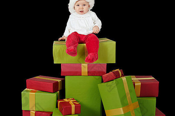 婴儿坐着堆栈圣诞节礼物孤立的黑色的背景