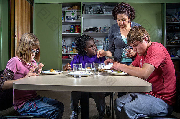 在老师的帮助下，一位盲人和<strong>残疾儿童</strong>在盲童学习中心的烹饪课上品尝食物。