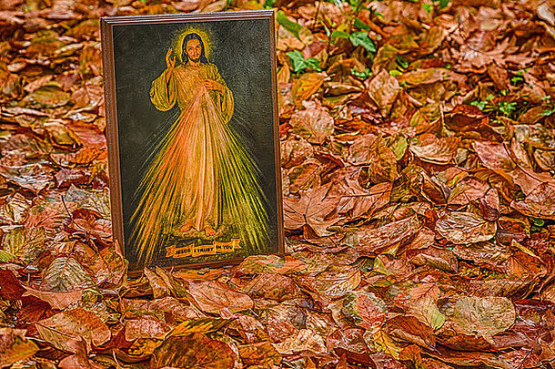 在秋天的落叶中画着仁慈的耶稣的图标：丝带上的句子耶稣，我相信你