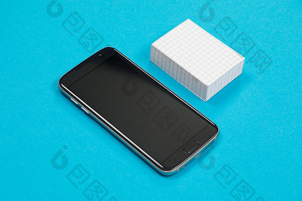 黑色的手机和一堆白色的刮擦纸分别放在蔚蓝的表面上