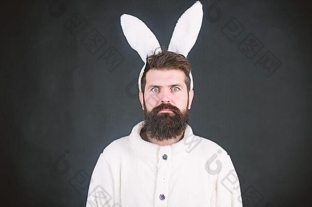 象征复活节的白色兔子。柔嫩的。黑色背景上长着兔子或兔子耳朵的家伙。享受温柔。复活节的气氛。男人英俊的脸上戴着白色的兔子耳朵。复活节兔子。
