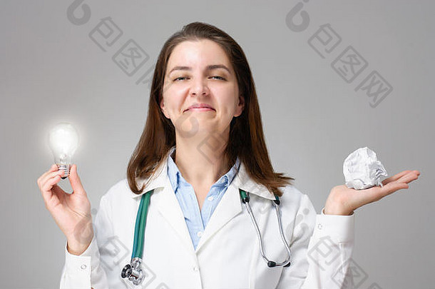 女医生持有发光的光灯泡皱巴巴的纸球