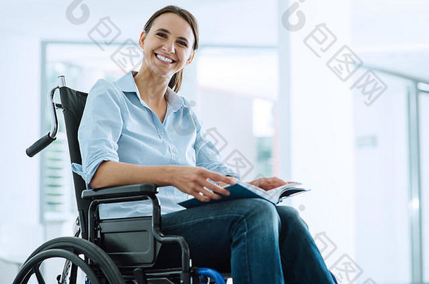坐在轮椅上微笑的年轻女子看着摄像机