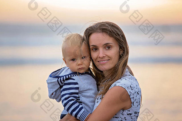 英国德文郡退潮时，年轻的母亲带着她美丽的孩子在海上欣赏日落