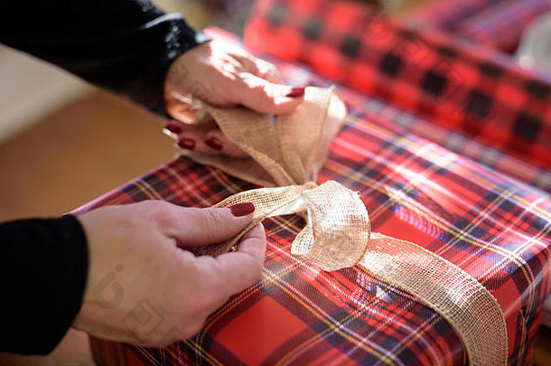 妇女包装礼物的特写镜头在圣诞礼物上系蝴蝶结