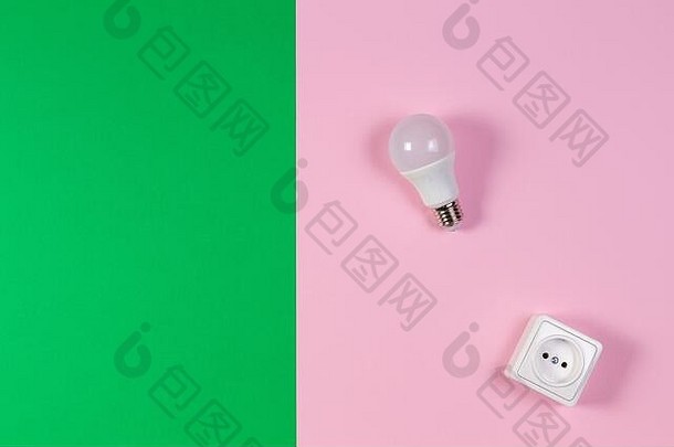 绿色和浅粉色背景上的白色电源插座和灯泡。俯视图