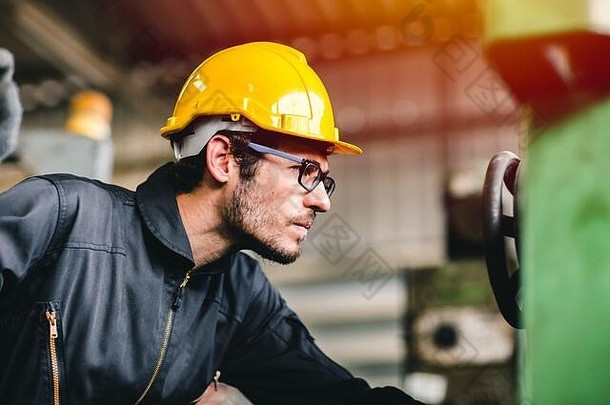 在工业工厂工作时，认真的工人、工程师注意看着机器，穿着安全服和头盔。