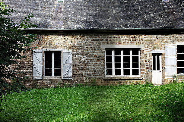 这是一张法国诺曼底一个农场房子的细节照片。我们可以看到门窗。前面有草