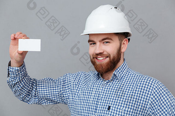 灰色背景上，一位留着快乐胡须的建筑商手持copyspace名片。