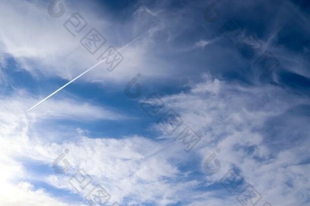飞机在蓝天上凝结的轨迹在一些美丽的云朵之间
