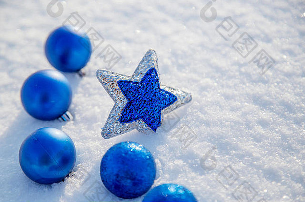 在阳光明媚的日子里，雪地里的圣诞蓝球和星星