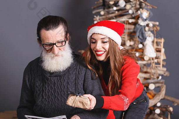 穿着红色毛衣、戴着<strong>圣诞</strong>帽的漂亮长发女儿送给她大胡子、穿着灰色毛衣、新年、<strong>圣诞</strong>节、节假日、纪念品、礼物、<strong>购</strong>物、折扣、商店、雪人<strong>圣诞</strong>老人、化妆、发型、<strong>狂欢</strong>节的老父亲。