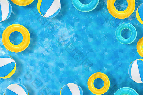海滩球和游泳圈漂浮在池顶视图上，并留有空白