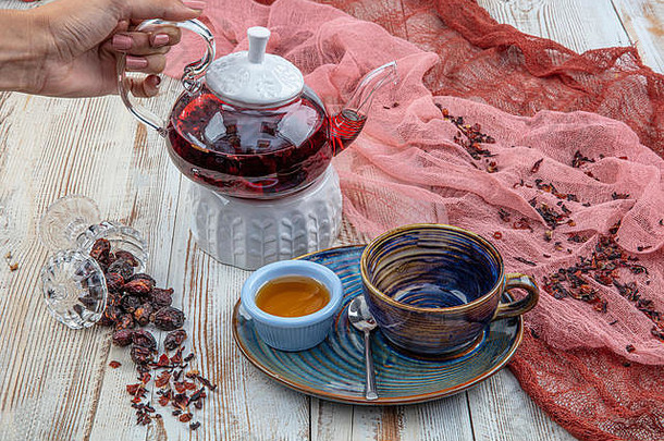 玫瑰果茶：在木制背景上冲泡茶、茶道、一杯新鲜酿造的玫瑰果茶。