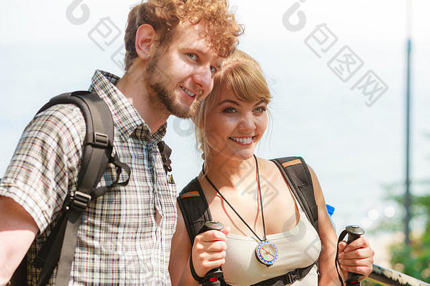 两个年轻人在海边徒步旅行。背包客夫妇在暑假旅行。拿着<strong>登山杖</strong>的女人。