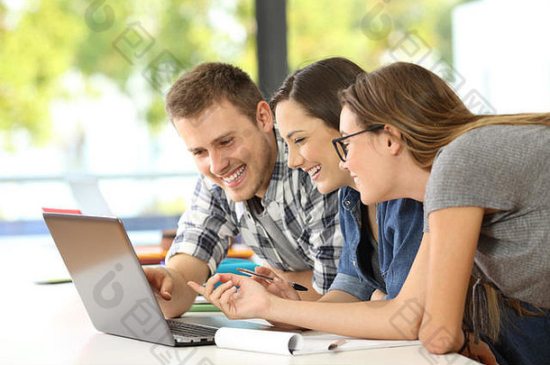 三个快乐的学生在教室里用<strong>笔记</strong>本电脑在线学习