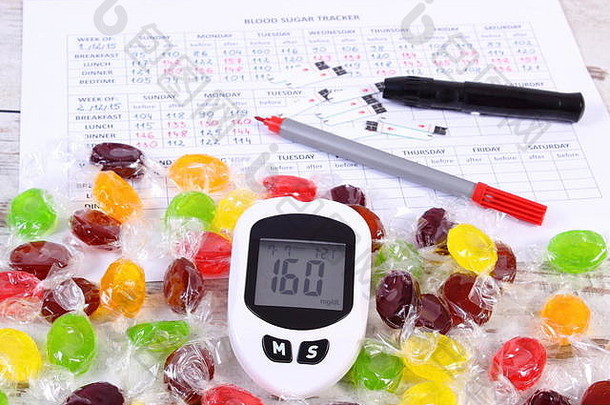 血糖仪、笔和彩色糖果在医疗表格上显示血糖水平测量结果，并进行检查