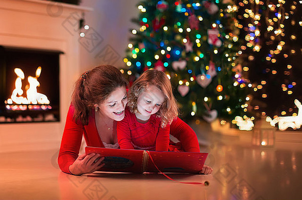平安夜，母亲和女儿在壁炉旁看书。一家人带着孩子庆祝圣诞节。用树装饰的房间