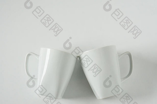 2个单色白色咖啡杯，白色<strong>背景</strong>，在欢呼声中叮当作响，空白的空间用于文本、复印或复印。现代顶视图公司