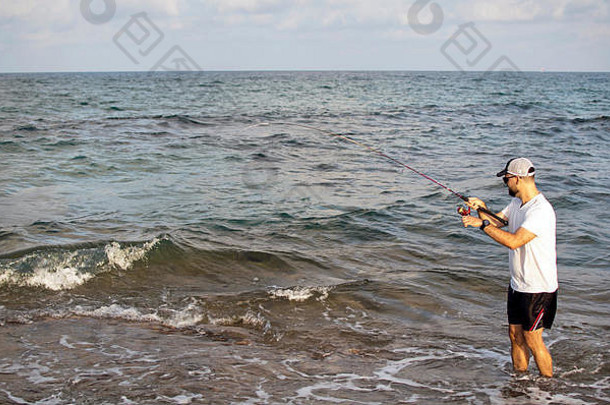 渔夫站海滨钩子鱼运动员持有钓鱼杆卷钩状的鱼自旋钓鱼爱好鱼抓海滩西班牙