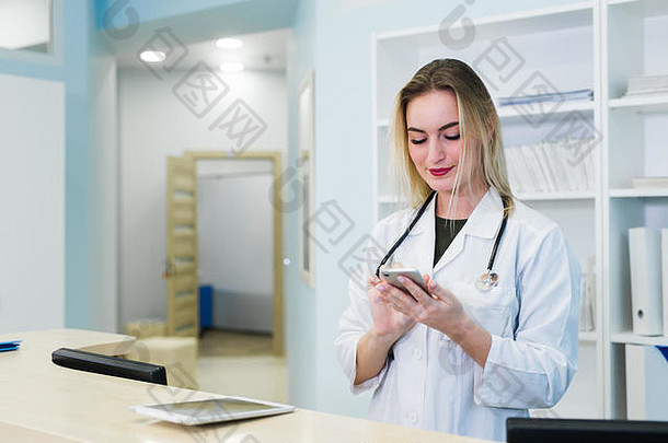 一位面带微笑的女医生戴着刷子在医院接待处工作，她正在剪贴板上写一份医疗报告并安排预约