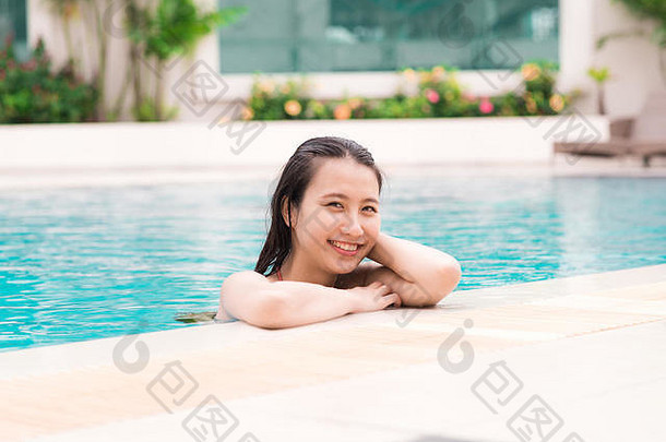 美丽的亚洲女子在游泳池里微笑