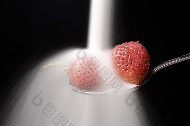 糖倒在勺子上，草莓被隔离在黑色背景上。