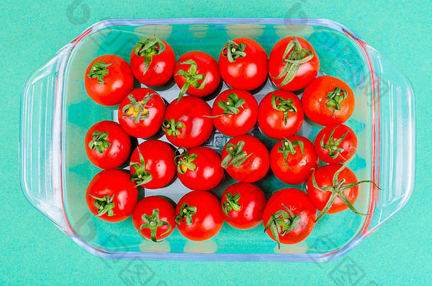 绿色背景下，碗中的红色成熟小樱桃西红柿。摄影棚照片