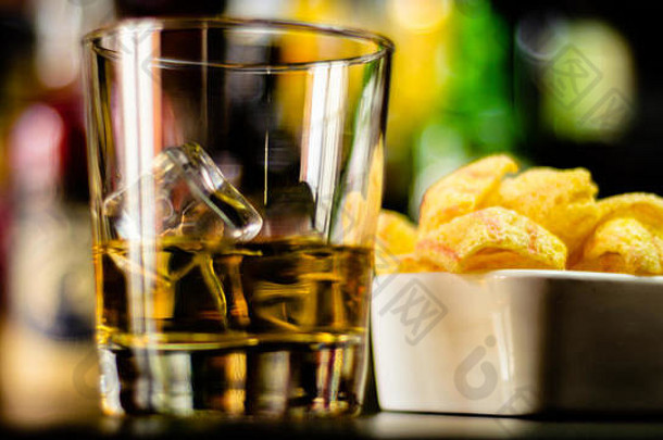 聚会时间，酒吧背景上有一杯威士忌、冰块和<strong>咸点心</strong>