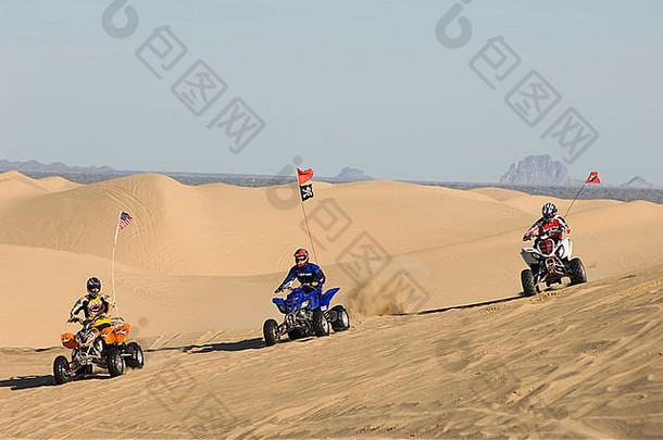 三名年轻男子在沙丘上驾驶ATV