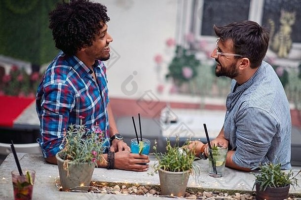 两个年轻人在咖啡馆花园里友好交谈