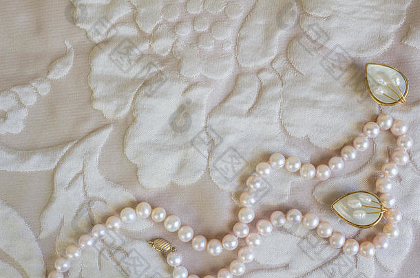 珍珠项链和珍珠母耳环，浅玫瑰色缎质背景/粉色珍珠串和两颗白色珍珠母耳钉