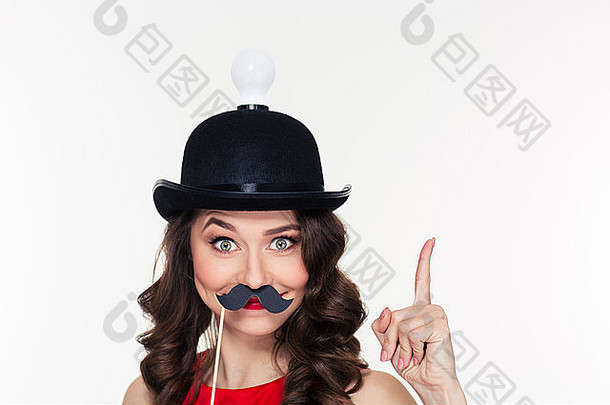 快乐滑稽的小卷发女孩，戴着有趣的黑帽子，灯泡朝上，并使用假胡子道具