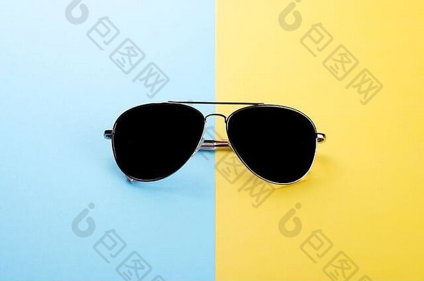 蓝色黄色背景的太阳镜是夏季保护眼睛的概念。
