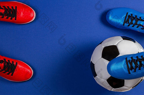蓝色背景上足球和两双足球运动鞋的俯视图