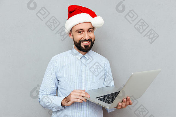 微笑有胡子的男人。业务衣服圣诞节他持有移动PC电脑相机灰色的背景