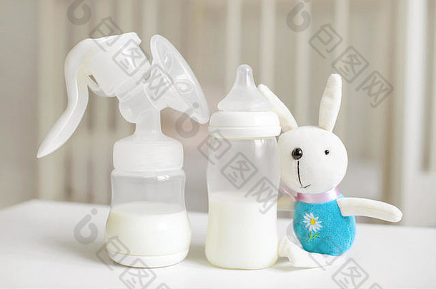 手动吸奶器，婴儿奶瓶，儿童房模糊背景下的兔子玩具。