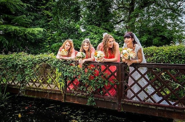 一位漂亮的新娘和她的伴娘站在一座华丽的桥上，一边笑着，一边在谢德尔的庄园酒店拍结婚照