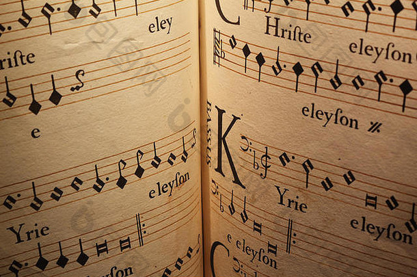 写在羊皮纸上的旧乐谱，为一首拉丁文歌曲展示了几根带音符的木棍和一个缩影