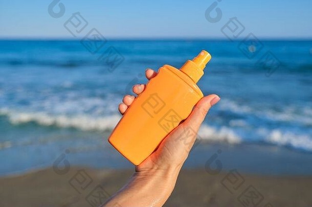 海滩上的女人手里拿着一瓶<strong>防晒乳</strong>液，