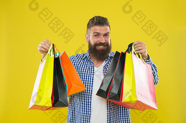 一个留着大胡子的时髦男人，一张欢快的脸，背着黄色背景的纸袋。享受黑色星期五的购物优<strong>惠</strong>。购物打折享受购物。让购物更快乐。