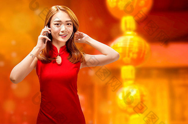 穿着旗袍的漂亮中国女人在红色背景下挂着灯笼打电话