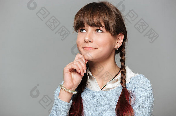 一个沉思微笑的女学生的特写照片，她用手臂托着下巴，望着远离灰色背景的复印空间
