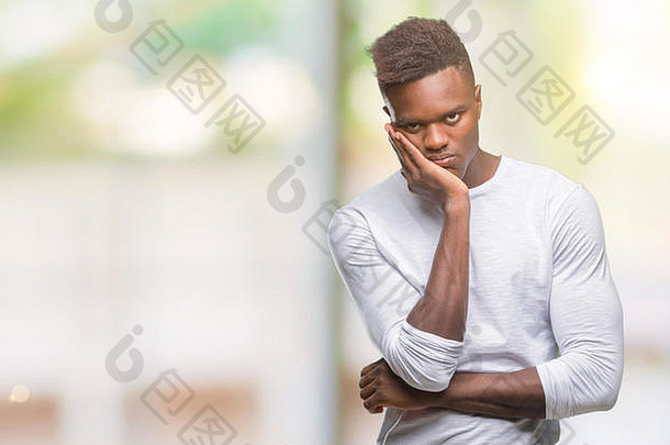 年轻的非裔美国男子在与世隔绝的背景下思考，双臂交叉，看起来很疲惫，对抑郁症感到厌倦。
