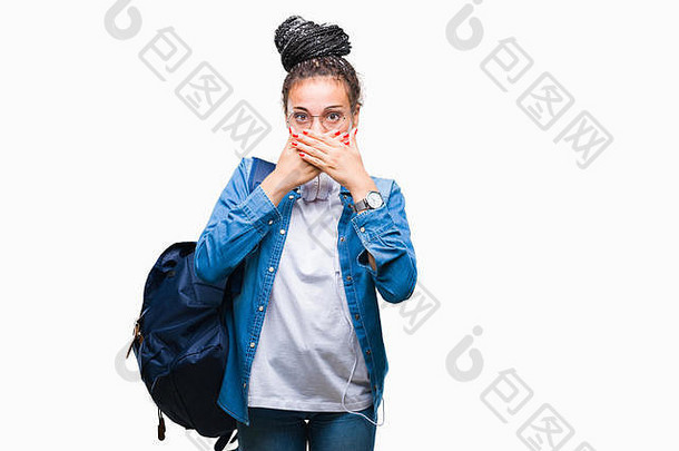 年轻的辫子头发的非裔美国女学生背着背包在孤立的背景下，震惊地用手捂住嘴，因为她犯了错误。秘密关注
