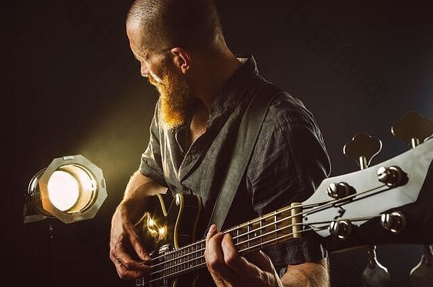 照片有胡子的男人。玩电吉他阶段前面聚光灯